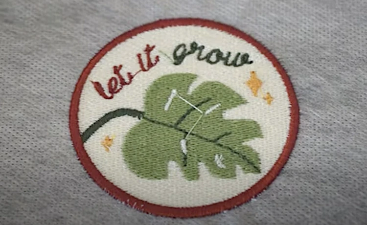 Environmental embroidered patch with an illustration of a leaf and the words "let it grow".