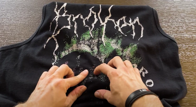 Designer discovering his artwork is cracking on his garment. He checks through picking at it with his fingers.