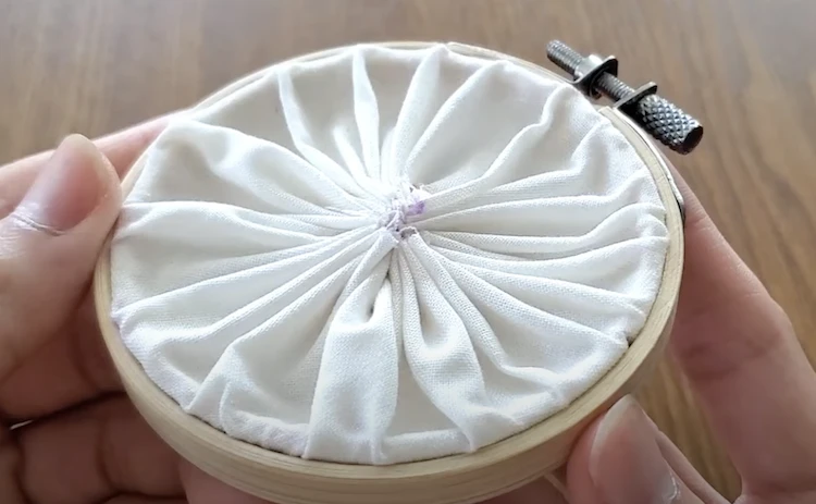 Embroider using a wooden hoop to keep fabric taut before hand sewing. 