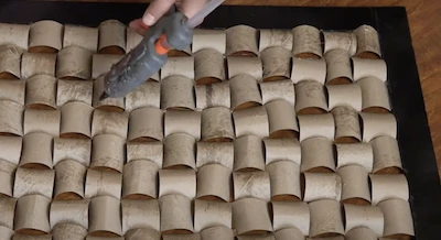 crafter creating wall art with toilet rolls using a glue gun