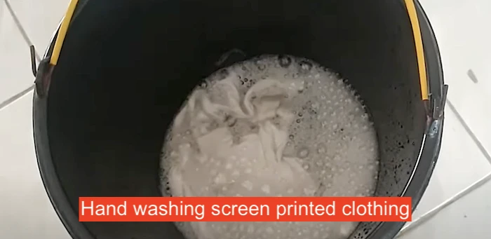 Cleaning screen prints in a bucket to prevent design fade.